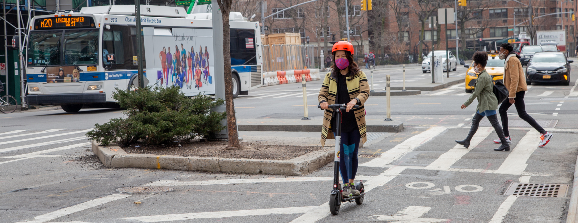 a person riding a scooter on 8th Avenue protected bike lane