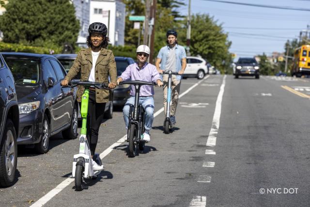 Three people riding e-scooters in a bike lane in the Bronx. 